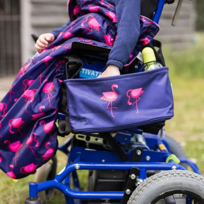 Bundlebean flamingo wheelchair bag shown on the side of a child's wheelchair
