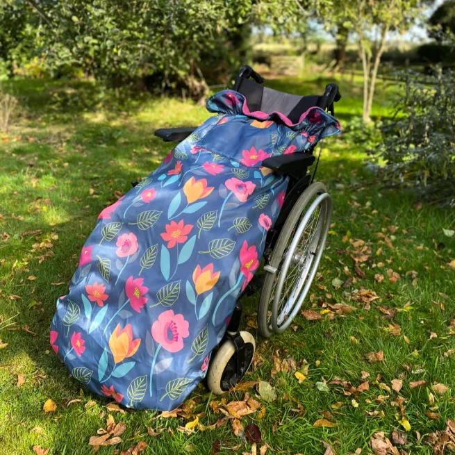 A wheelchair outside in a field with the multicolour floral cosy on the chair