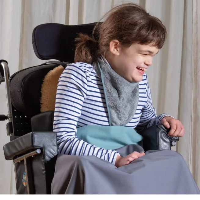 Girl in wheelchair wearing grey bamboo towelling kerchief with grey wheelchair cover