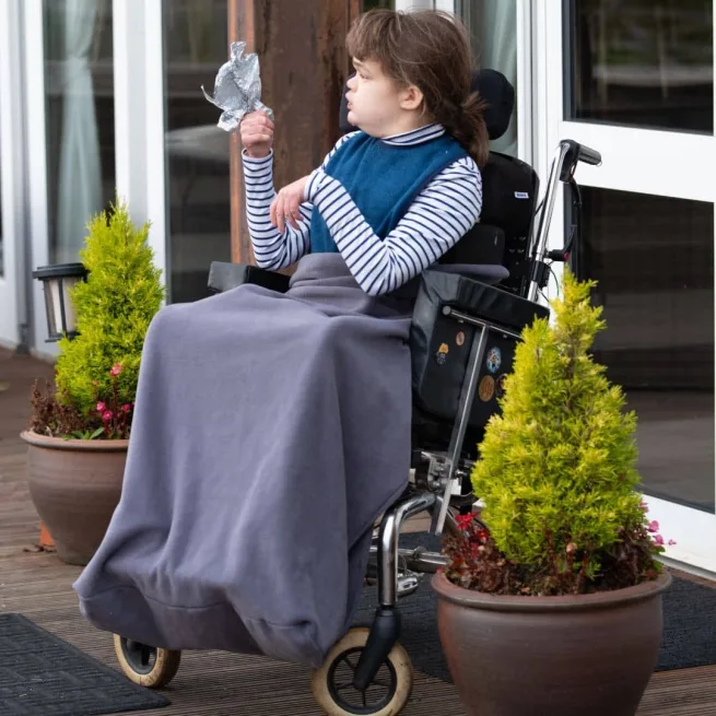Girl wearing grey fleece wheelchair leg cover