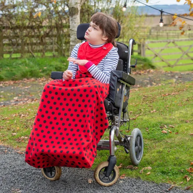 Girl wearing red fleece wheelchair cover
