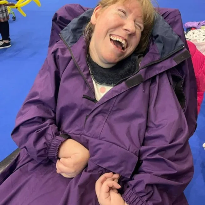 Person smiling wearing purple wheelchair coat