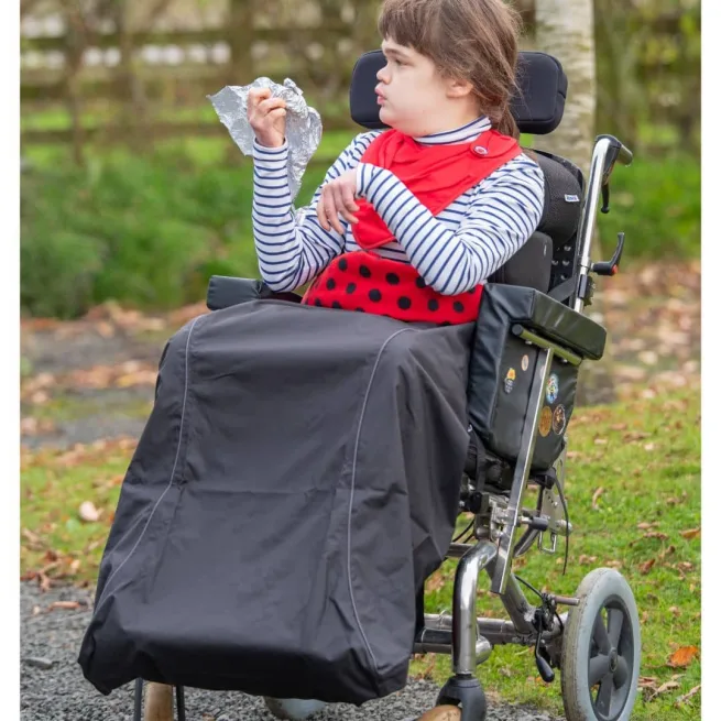 Girl wearing waterproof wheelchair leg cover in black with red spot fleece