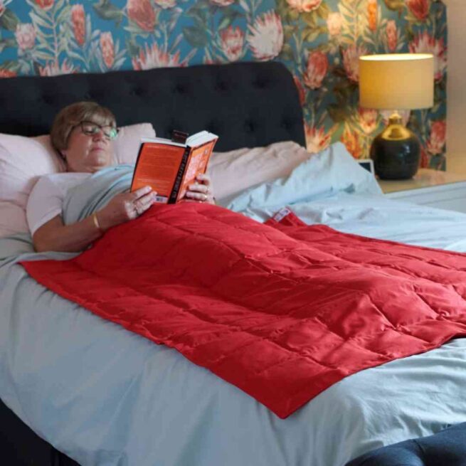 Person in bed with red weighted blanket