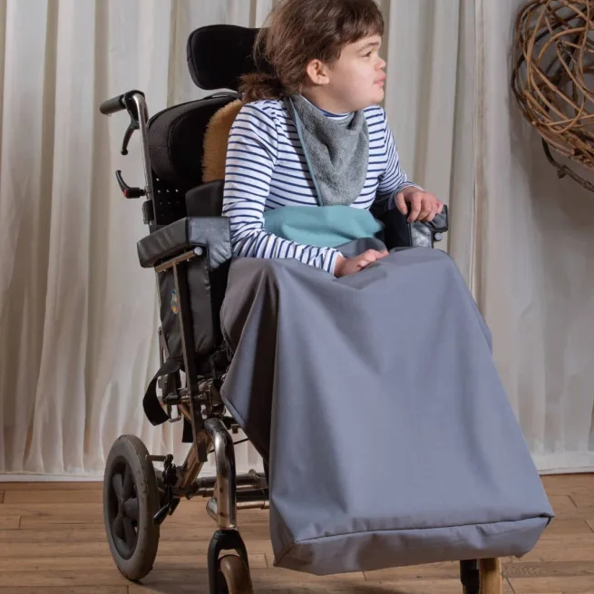 Girl in wheelchair wearing grey kerchief and sage green and grey leg wheelchair cover