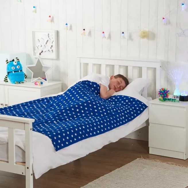 Boy in bed with weighted blanket in blue star design