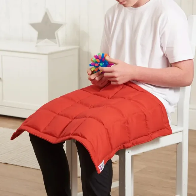 boy sat in chair with red weighted lap pad on legs