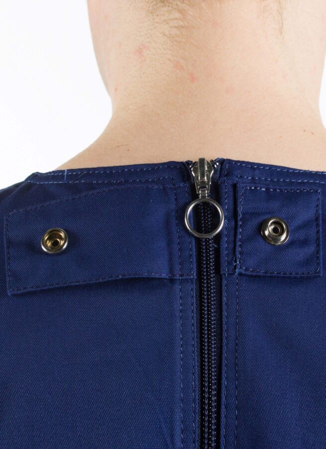 Close up of male wearing 4Care Rip Resistant bodysuit zipper fastening and press closure button in navy