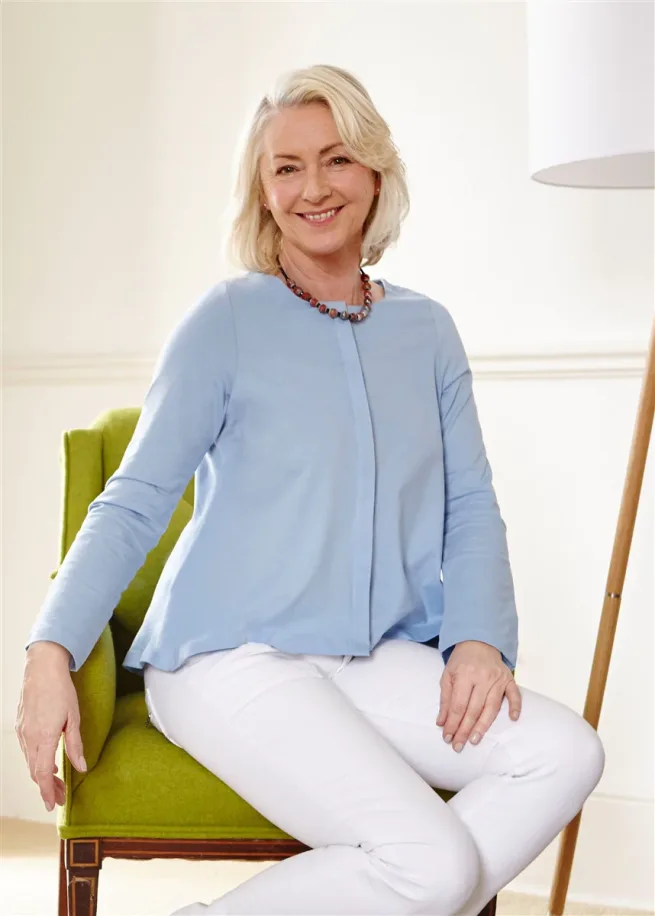 Women sitting wearing The Able Label blue top with white jeans