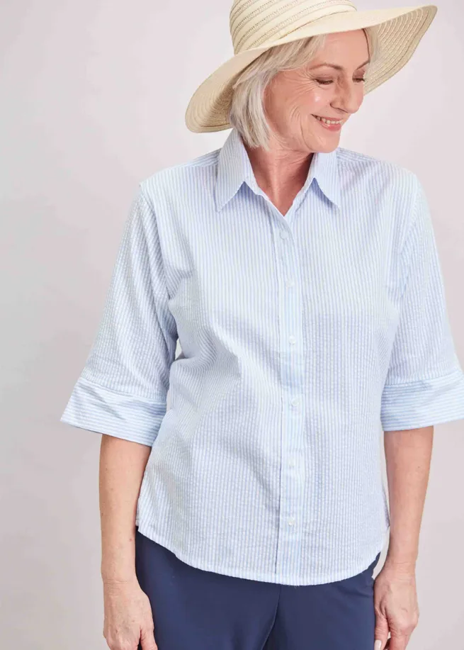 Woman wearing soft blue Camilla shirt, blue trousers and straw hat