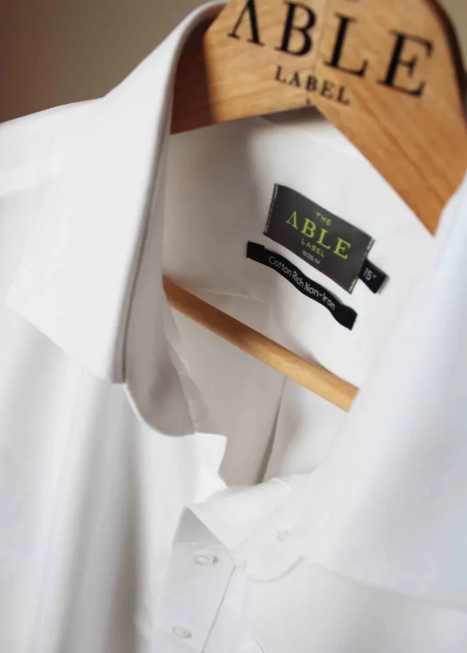 Close up of white shirt on wooden hanger, showing the velcro fastening