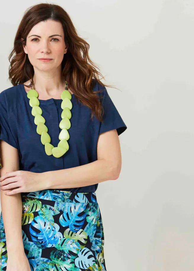Women wearing tabatha navy short sleeve top with lime necklace and print skirt