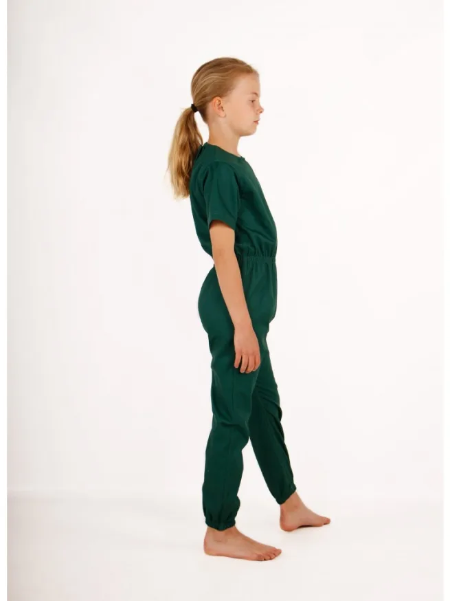 Girl standing wearing green rip resistant bodysuit, short sleeves, long legs, side view
