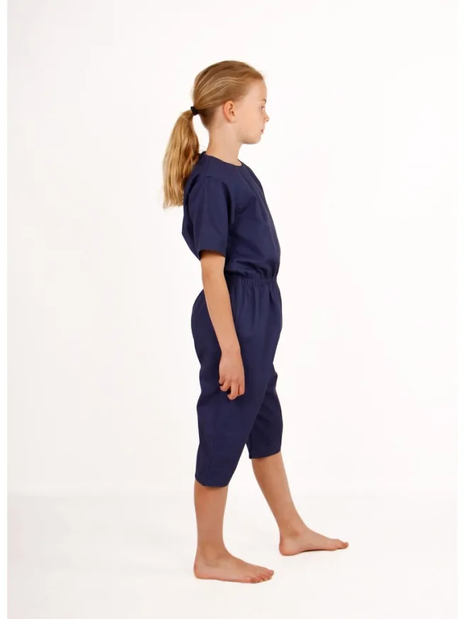 Girl standing wearing navy rip resistant bodysuit, short sleeves, knee length, side view