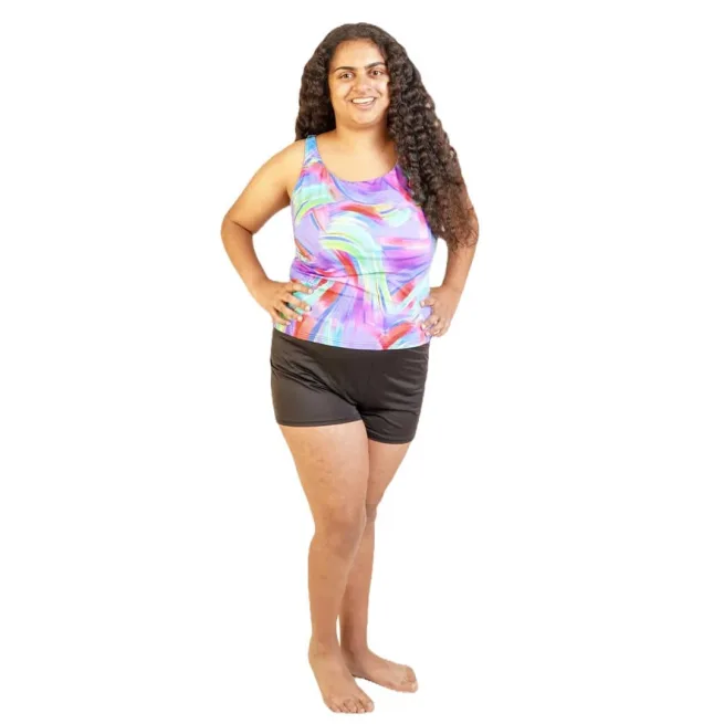 Model standing wearing Kes-Vir ladies tankini in indigo wave top and black shorts
