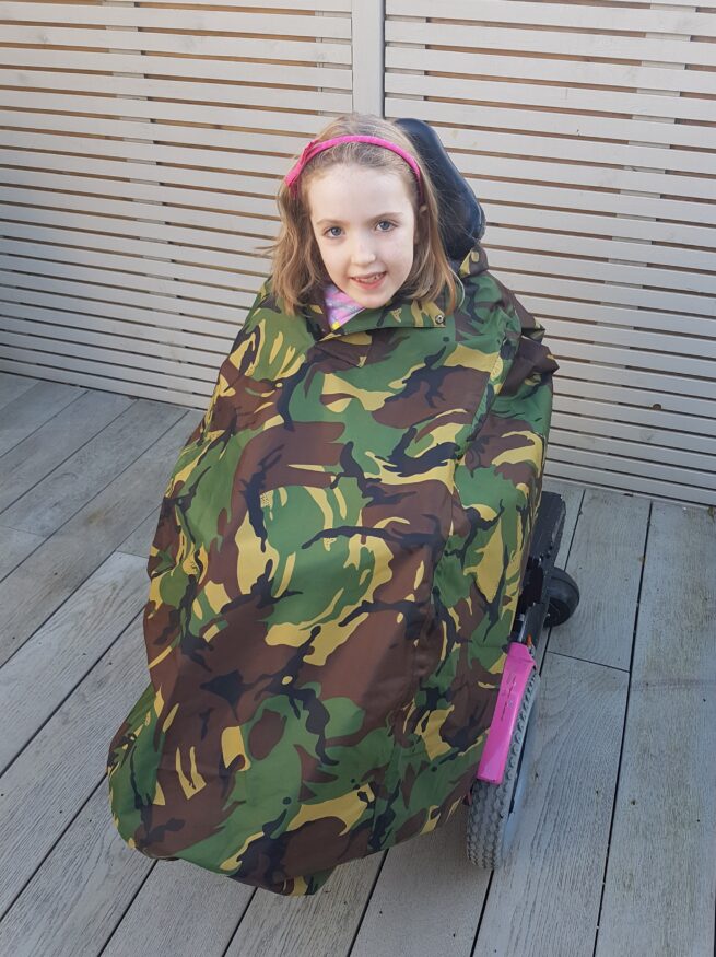 Girl in wheelchair wearing camo waterproof coverall