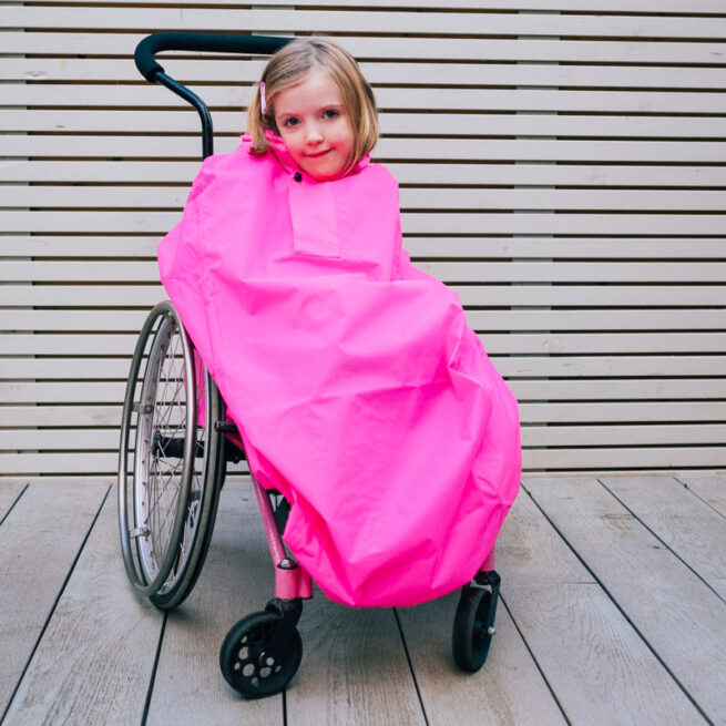 Girl in wheelchair wearing pink waterproof coverall